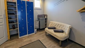 A room with a white sofa, a blue locker area, and a small window. - Charming Roulotte Stay: Streamside Serenity, Sauna, Massage & Ideal for Family or Friends (Ferdrupt)