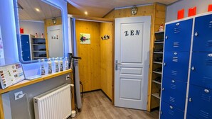A room with a vanity mirror, a door labeled "ZEN", and blue lockers. - Charming Roulotte Stay: Streamside Serenity, Sauna, Massage & Ideal for Family or Friends (Ferdrupt)