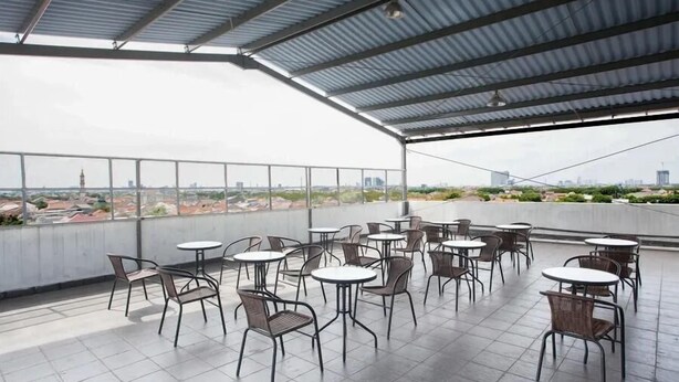Une terrasse sur le toit, dotée de nombreuses tables et chaises, offrant une vue panoramique sur la ville.