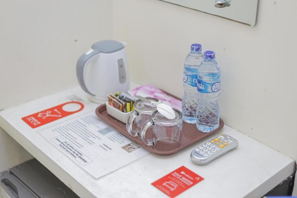 A hotel room with a tray table, a kettle, two bottles of water, a remote control, and a menu.