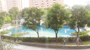 A swimming pool surrounded by trees and a brick wall, with a building in the background. - Starlake Daewoo Managed by Anstay Ha Noi (Hanoi)