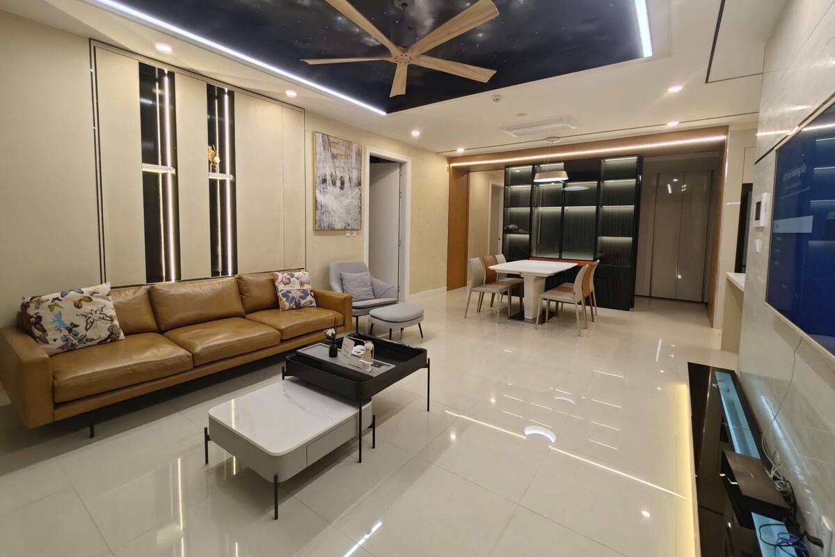 A modern living room with a sofa, coffee table, and a dining area with chairs and a table.