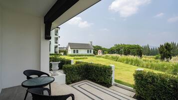A balcony with a view of a well-maintained lawn and a house in the background.