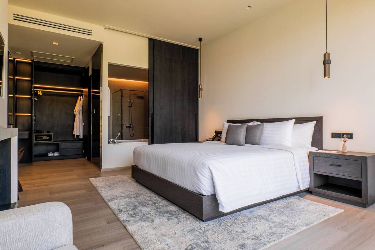 A modern bedroom with a large bed, bedside table, and a walk-in closet.