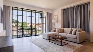 A modern living room with a large sliding glass door, a sofa, a coffee table, and a lamp. - Estella Khao Yai (Pak Chong)