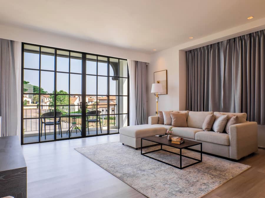 Una sala de estar moderna con un gran ventanal corredero, un sofá, una mesa de centro y una lámpara.