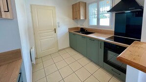 Eine Küche mit Herd, Backofen, Spüle und Holzschränken.