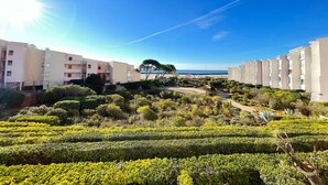 A residential area with apartment buildings, a well-maintained garden, and a clear view of the sea.