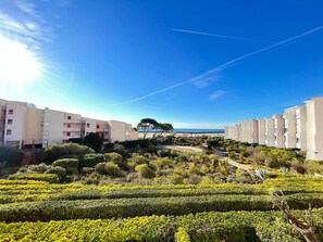 A residential area with apartment buildings, a well-maintained garden, and a clear view of the sea.