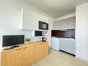 A compact kitchen with a microwave, a coffee maker, and a small refrigerator.