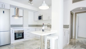A modern kitchen with white cabinetry, a built-in oven, a microwave, and a pendant light above the island. - Beautiful 3-bedroom apartment with terrace in Nueva Andalucía, Marbella (Marbella)
