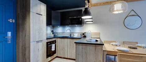 A modern kitchen with wooden cabinetry, a built-in oven, and a dining area with a wooden table and chairs.