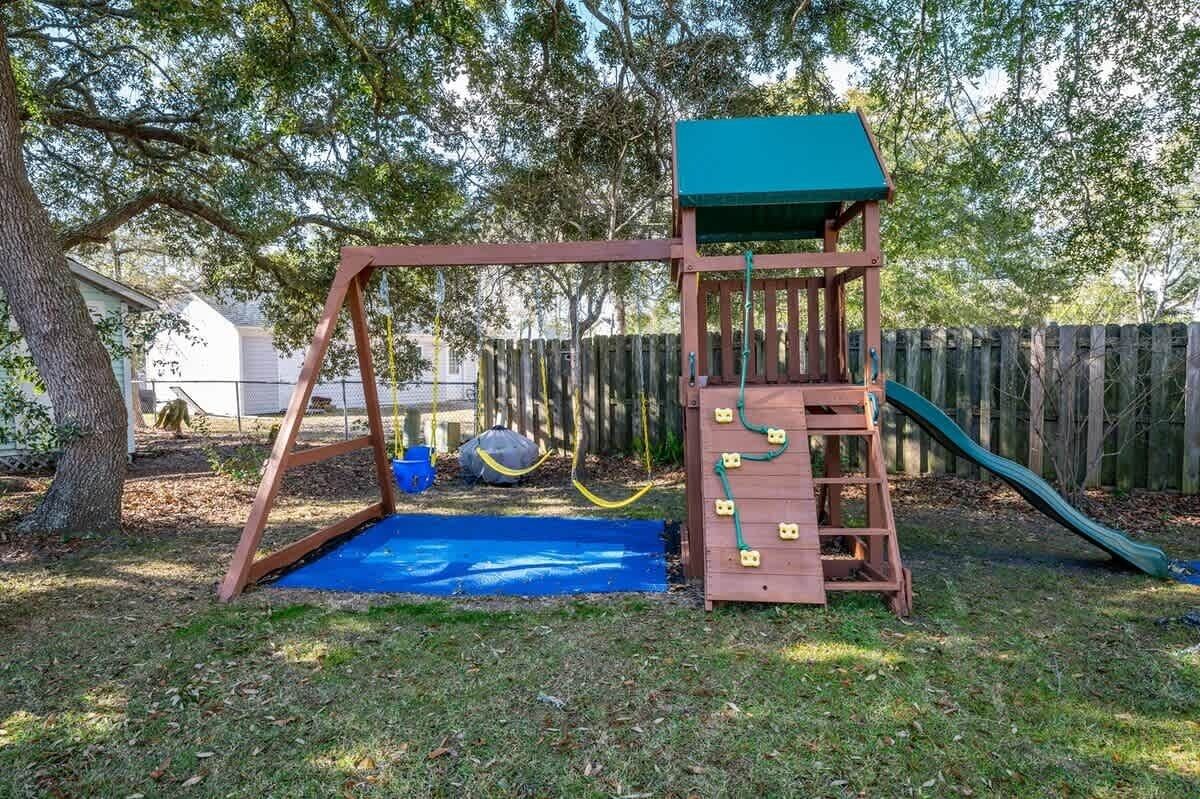 A wooden swing set with a green roof and a slide in a backyard.