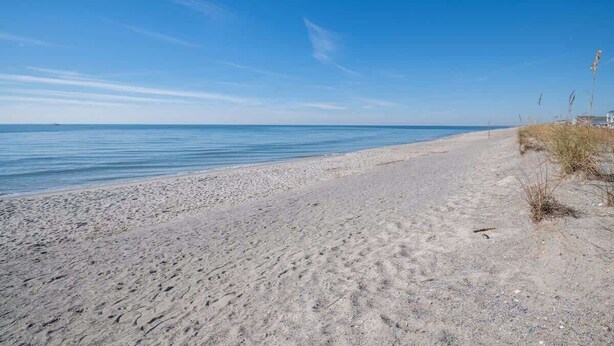 A beach with a clear sky and calm sea. - Sunny and Chair: Early Bird Special! (Oak Island)