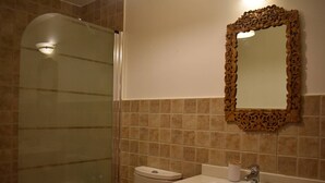 Ein Badezimmer mit Duschkabine, Toilette, Waschbecken mit Spiegel und Handtuchhalter.