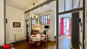 A dining area with a round table, chairs, a chandelier, and a television. - T2 Apartment in Mont-Dore, 4 pers, pets allowed, WiFi (Mont-Dore)