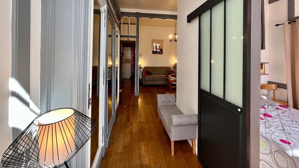 A narrow hallway with a sofa and a bed on the right, a lamp on the left, and a door at the end. - T2 Apartment in Mont-Dore, 4 pers, pets allowed, WiFi (Mont-Dore)