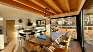 Een moderne keuken met een centraal eiland, houten balken in het plafond en grote ramen met uitzicht op de omgeving.