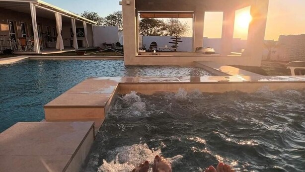 Ein Poolbereich mit Whirlpool und überdachter Sitzgelegenheit.