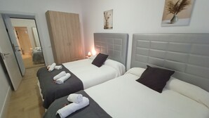 Ein Hotelzimmer mit zwei Betten, einem Kleiderschrank, einem Nachttisch mit Lampe und einem gerahmten Kunstwerk an der Wand.