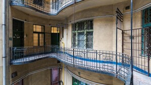 Un edificio de varios pisos con balcones, una escalera central y un patio.
