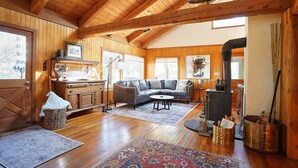 A cozy cabin interior with a wooden ceiling, a fireplace, a sofa, and a dining table. - Peaceful and spacious home tucked away at the base of the Mission Mountains. (St. Ignatius)