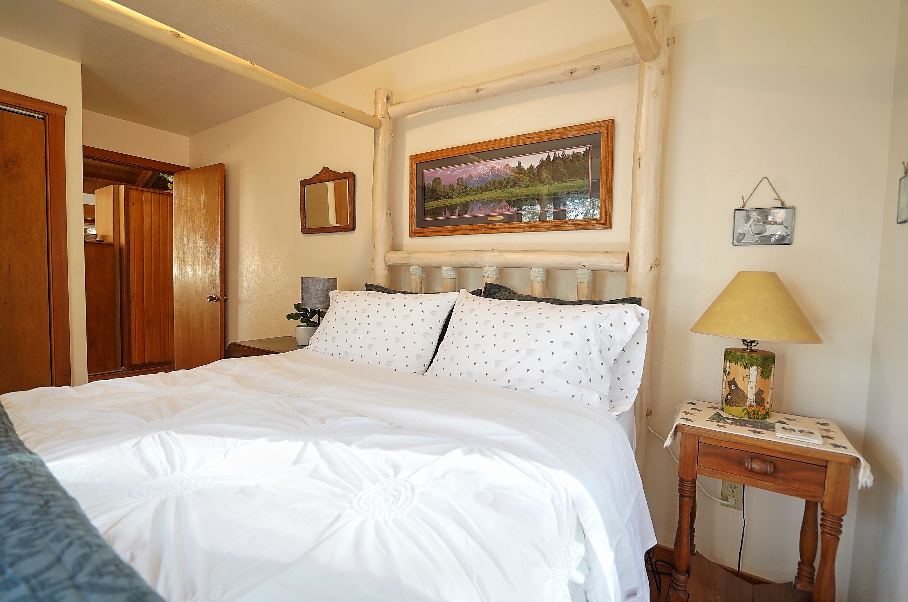 Een opgemaakt bed met witte lakens en een hoofdbord met een spiegel erboven.