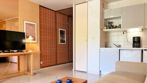 A compact living space with a TV, a coffee maker, and a kitchenette.