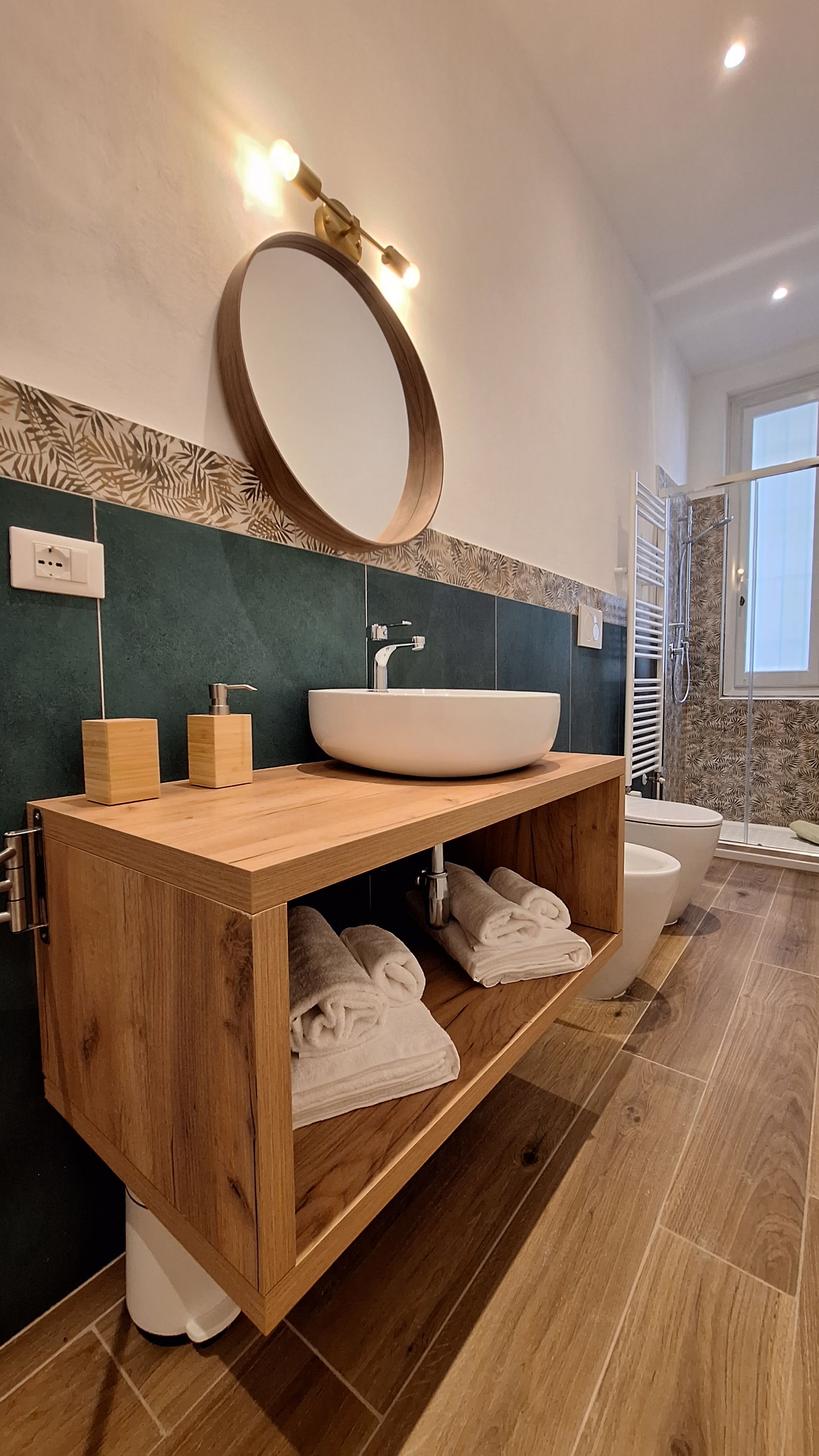 A modern bathroom with a wooden vanity, a large oval mirror, and a white sink.