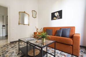 A living room with a glass coffee table, an orange sofa, and a framed picture on the wall. - Casa Gin Tonic, quiet house with terrace (Firenze)