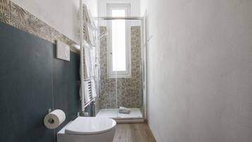 Un bagno con il water, una doccia e un porta asciugamani.