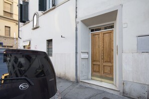 A black car parked on a street, a white building with a wooden door, and a mailbox. - Casa Gin Tonic, quiet house with terrace (Firenze)