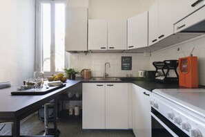 Une cuisine avec des meubles blancs, un plan de travail noir, un évier et une cuisinière.