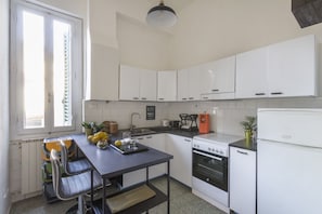 A kitchen with white cabinets, a stove, a sink, and a window with blinds. - Casa Gin Tonic, quiet house with terrace (Firenze)