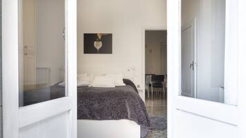 Una camera da letto con un letto, un quadro appeso al muro e una porta che dà su un'altra stanza.
