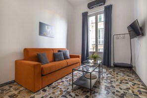 A living room with a sofa, a coffee table, a TV, and a window with curtains. - Casa Gin Tonic, quiet house with terrace (Firenze)