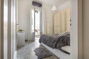 A bedroom with a bed, a wardrobe, a small bedside table with a plant, and a door leading to a balcony. - Casa Gin Tonic, quiet house with terrace (Firenze)