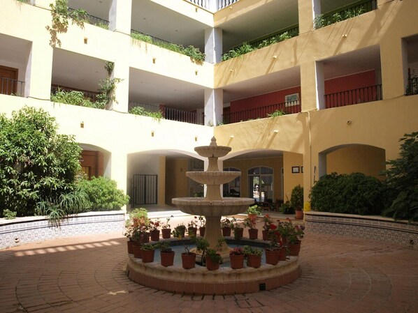 Un patio de varios niveles con una fuente central rodeada de plantas en macetas.