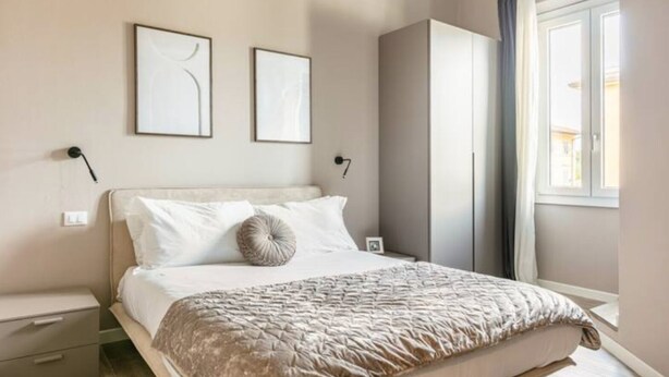 Une chambre à coucher comprenant un lit, des tables de chevet, une armoire et deux tableaux encadrés accrochés au mur.