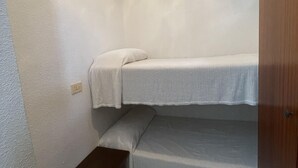 A small, single-bedded room with a bunk bed and a small wooden bench.