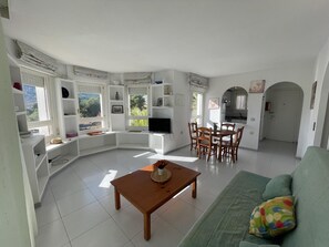 A spacious living area with a dining table, a sofa, and a TV.