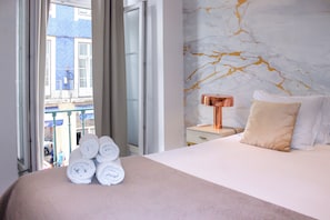Une chambre d’hôtel avec un lit, une table de chevet, une lampe et une vue sur l’extérieur.