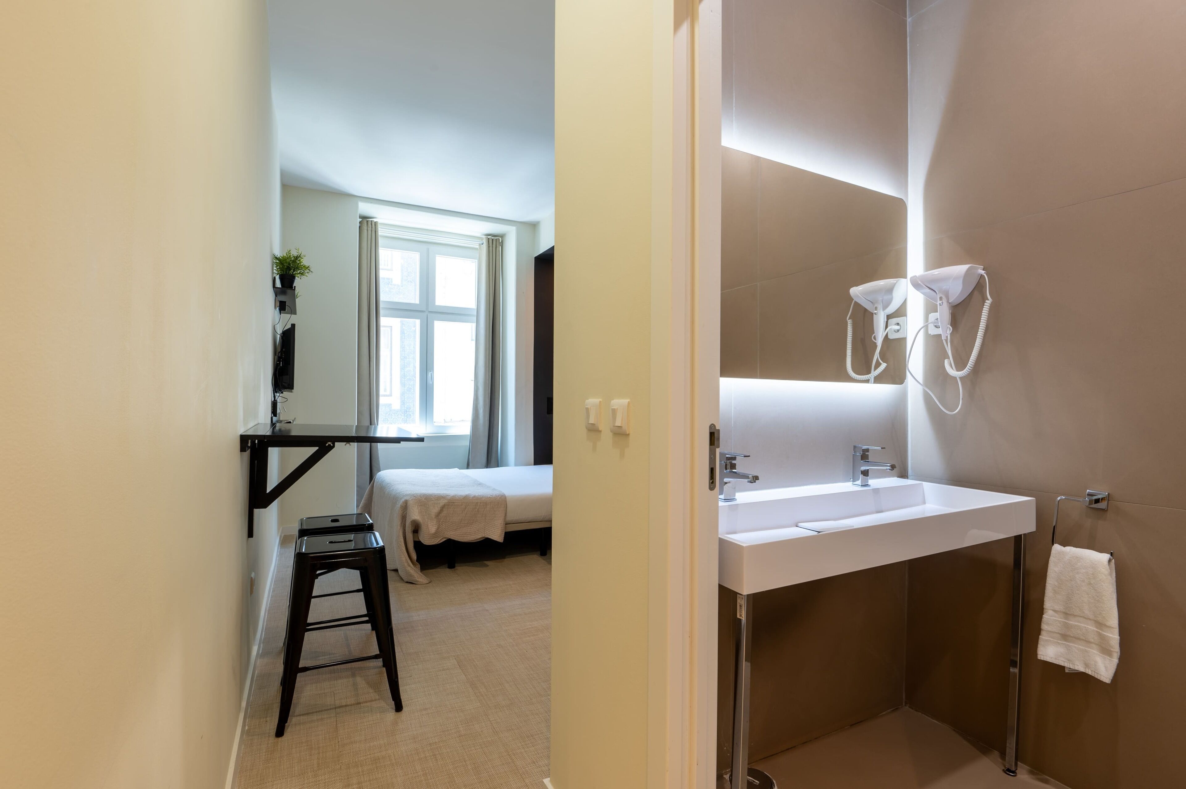 Une salle de bain moderne avec un grand miroir, un lavabo blanc et un porte-serviettes.