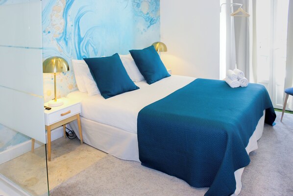 A bedroom with a bed, nightstands, a lamp, a towel rack, and a shower curtain.