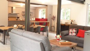 Een moderne woonkamer met een grijze bank, een houten salontafel en een eetgedeelte met een rode accentmuur.