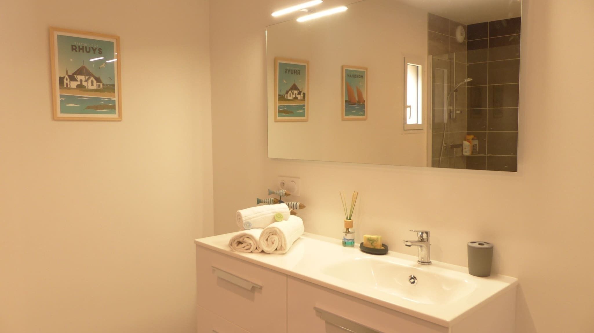 Un baño con lavamanos, espejo y dos cuadros en la pared.