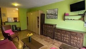 Ein Wohnzimmer mit braunem Sofa, einem Holztisch und einem an der Wand befestigten Fernseher.