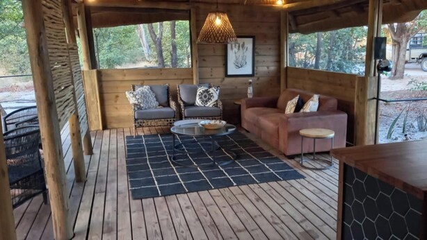 Una terraza de madera con un sofá, sillas y una mesa.