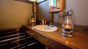 Un baño con tocador de madera, lavabo blanco, espejo y una linterna.