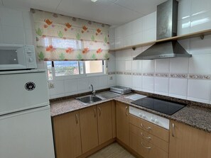 Una cocina equipada con microondas, estufa, pileta y muebles de madera.